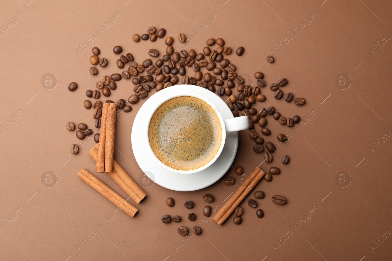 Cup of hot coffee, cinnamon and beans on brown background, flat lay Photo of Cup of hot coffee, cinnamon and beans on brown background, flat lay