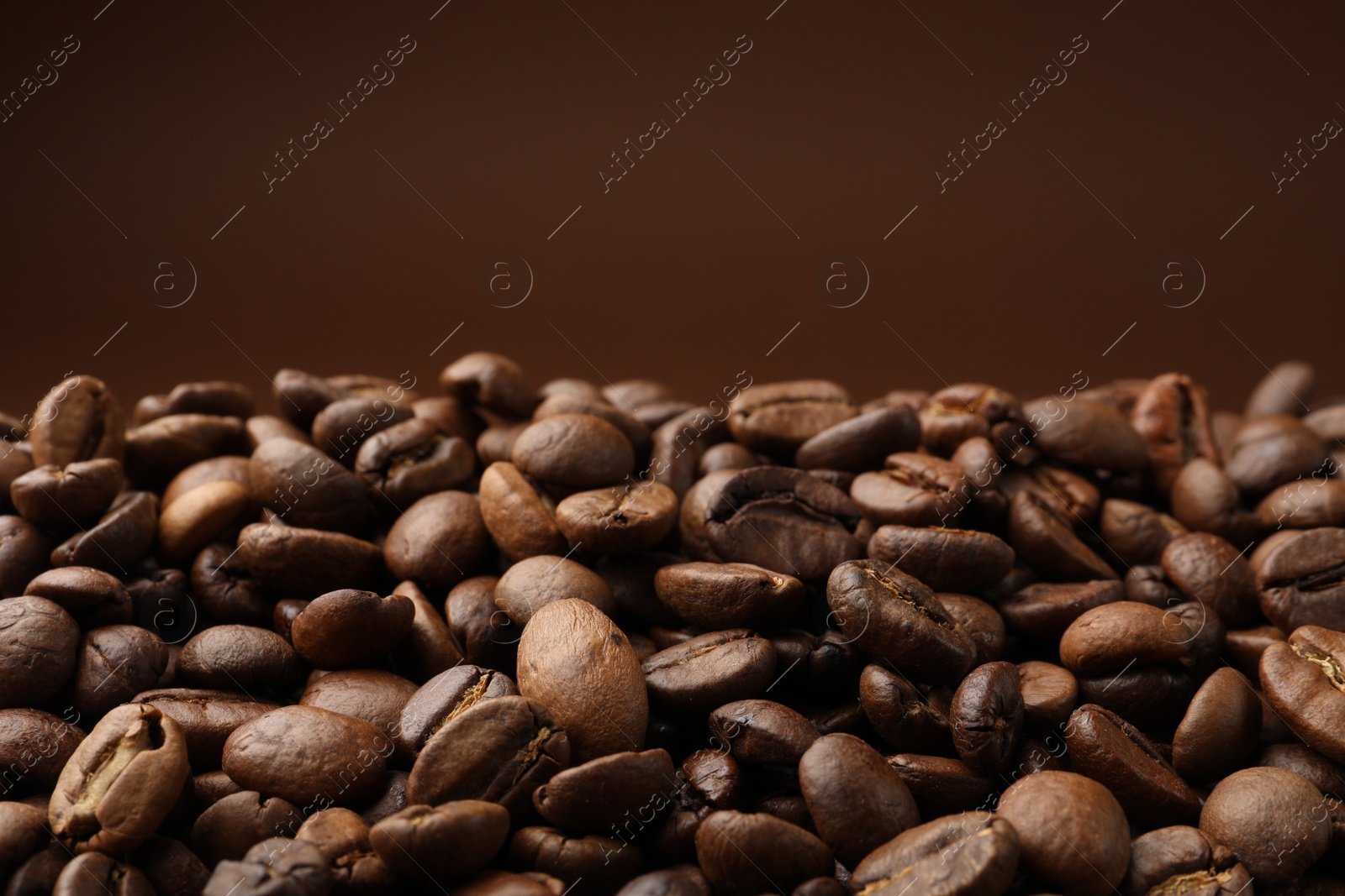 Pile of roasted coffee beans on brown background, closeup Photo of Pile of roasted coffee beans on brown background, closeup