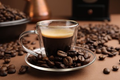 Photo of Cup of hot coffee and beans on brown background, closeup