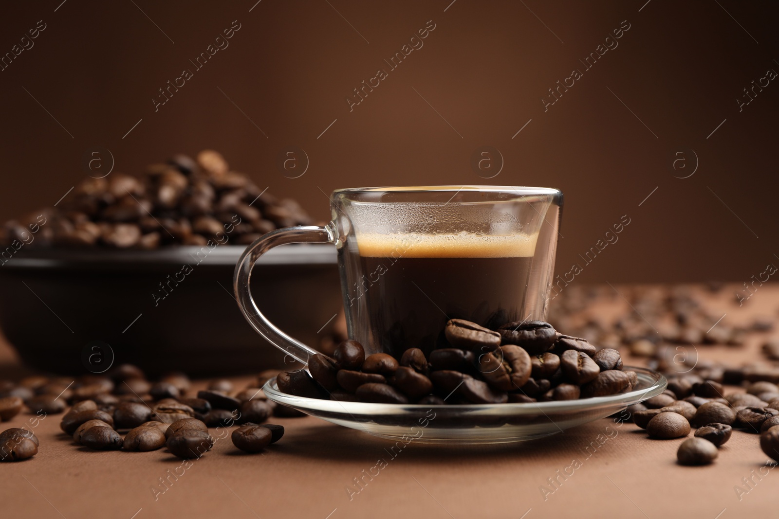 Cup of hot coffee and beans on brown background, closeup Photo of Cup of hot coffee and beans on brown background, closeup