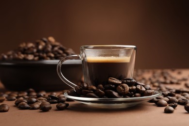 Photo of Cup of hot coffee and beans on brown background, closeup