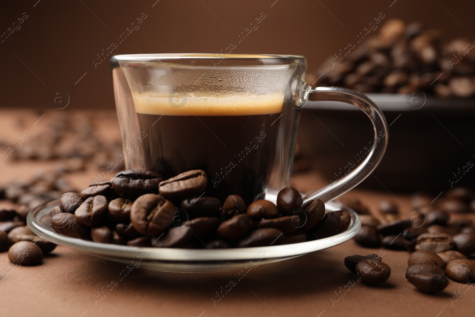 Cup of hot coffee and beans on brown background, closeup Photo of Cup of hot coffee and beans on brown background, closeup