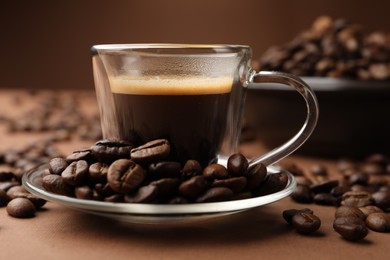 Photo of Cup of hot coffee and beans on brown background, closeup