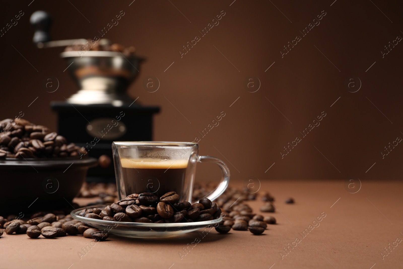 Cup of hot coffee, grinder and beans on brown background, closeup. Space for text Photo of Cup of hot coffee, grinder and beans on brown background, closeup. Space for text