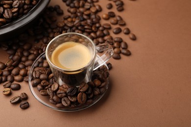 Photo of Cup of hot coffee and beans on brown background, closeup. Space for text
