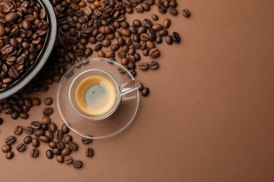 Photo of Cup of hot coffee and beans on brown background, flat lay. Space for text