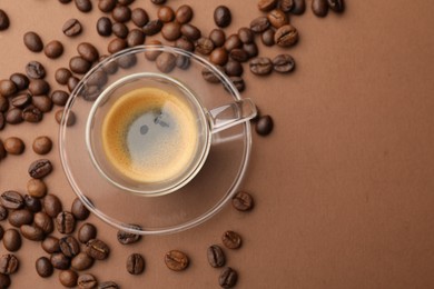 Photo of Cup of hot coffee and beans on brown background, flat lay. Space for text
