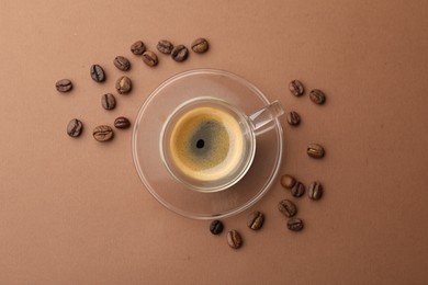 Photo of Cup of hot coffee and beans on brown background, flat lay