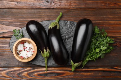 Photo of Fresh eggplants, parsley and spices on wooden table, top view