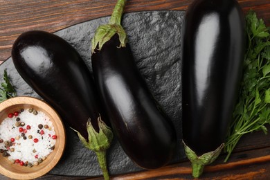 Photo of Fresh eggplants, parsley and spices on wooden table, top view