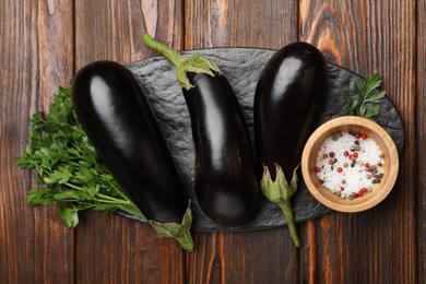 Photo of Fresh eggplants, parsley and spices on wooden table, top view