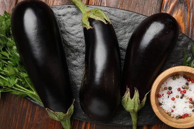 Photo of Fresh eggplants, parsley and spices on wooden table, top view
