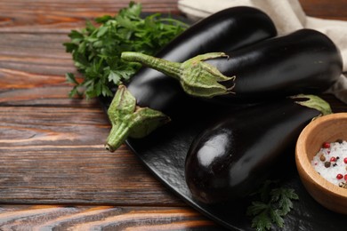 Photo of Fresh eggplants, parsley and spices on wooden table, closeup