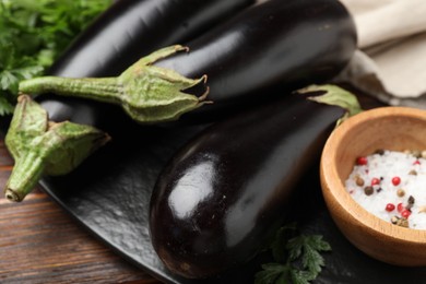 Photo of Fresh eggplants, parsley and spices on wooden table, closeup