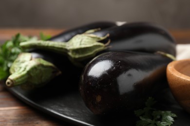 Photo of Fresh eggplants on wooden table against blurred grey background, closeup