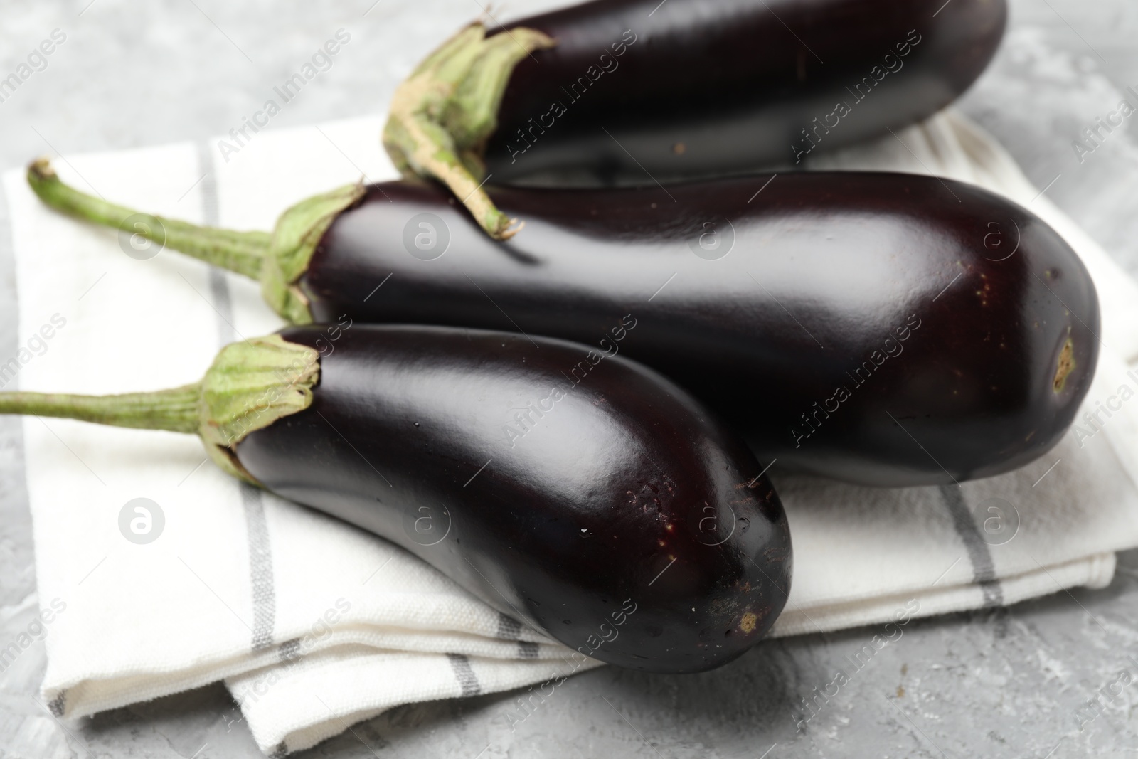 Fresh eggplants and napkin on grey textured table, closeup Photo of Fresh eggplants and napkin on grey textured table, closeup