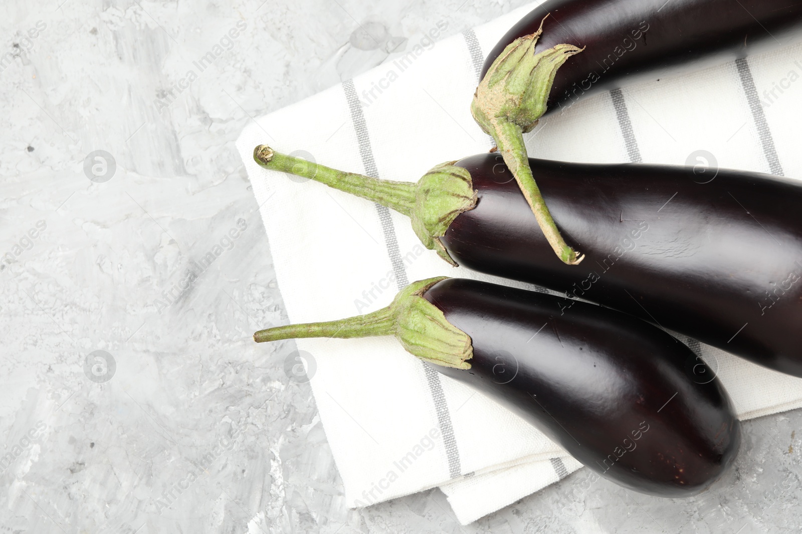 Fresh eggplants and napkin on grey textured table, top view. Space for text Photo of Fresh eggplants and napkin on grey textured table, top view. Space for text