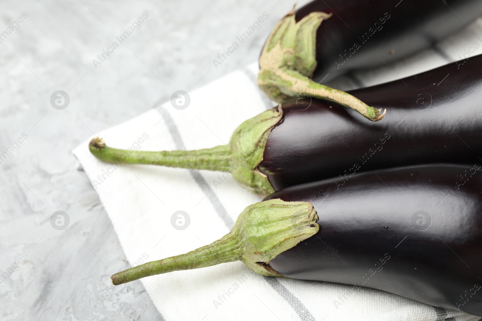 Fresh eggplants and napkin on grey textured table, closeup Photo of Fresh eggplants and napkin on grey textured table, closeup