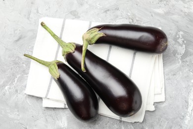 Photo of Fresh eggplants and napkin on grey textured table, top view