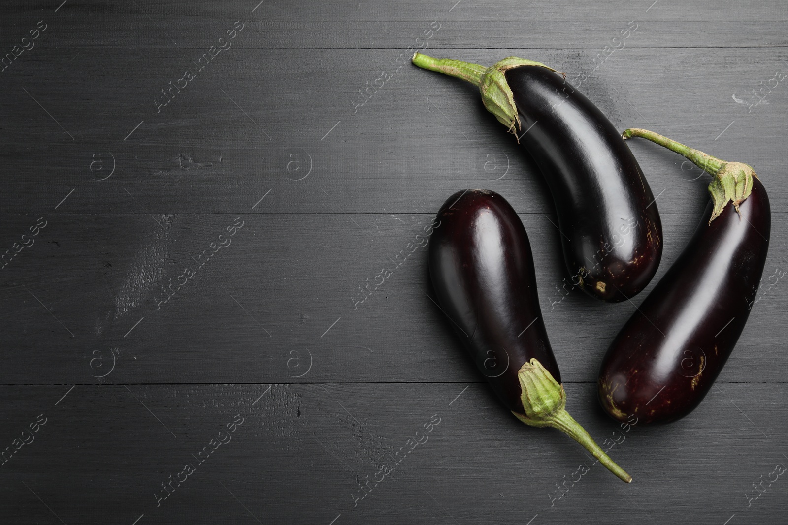 Photo of Fresh eggplants on black wooden table, flat lay. Space for text