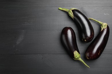 Photo of Fresh eggplants on black wooden table, flat lay. Space for text