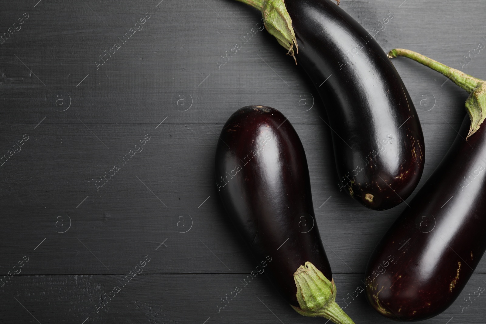 Photo of Fresh eggplants on black wooden table, flat lay. Space for text
