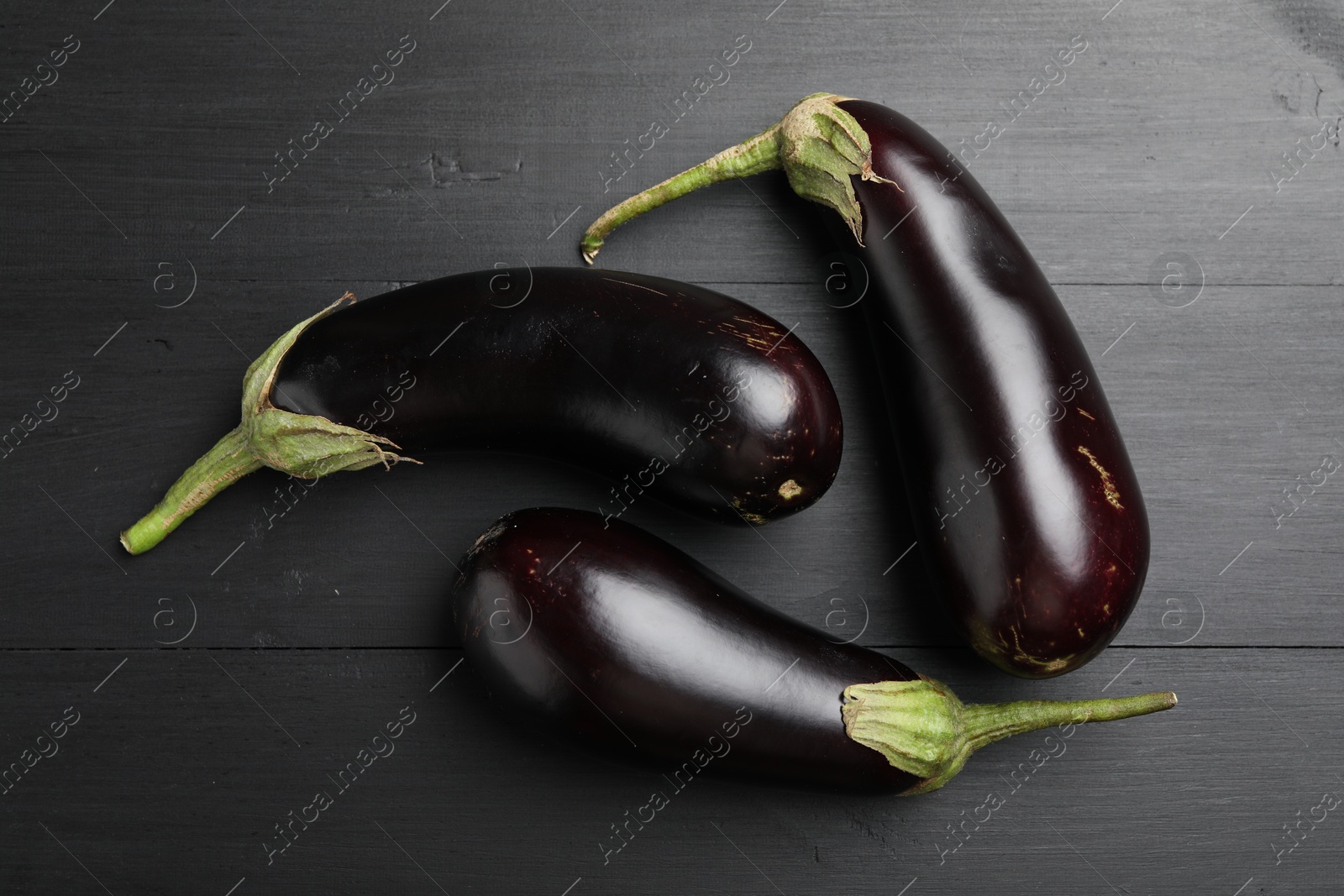 Photo of Fresh eggplants on black wooden table, flat lay