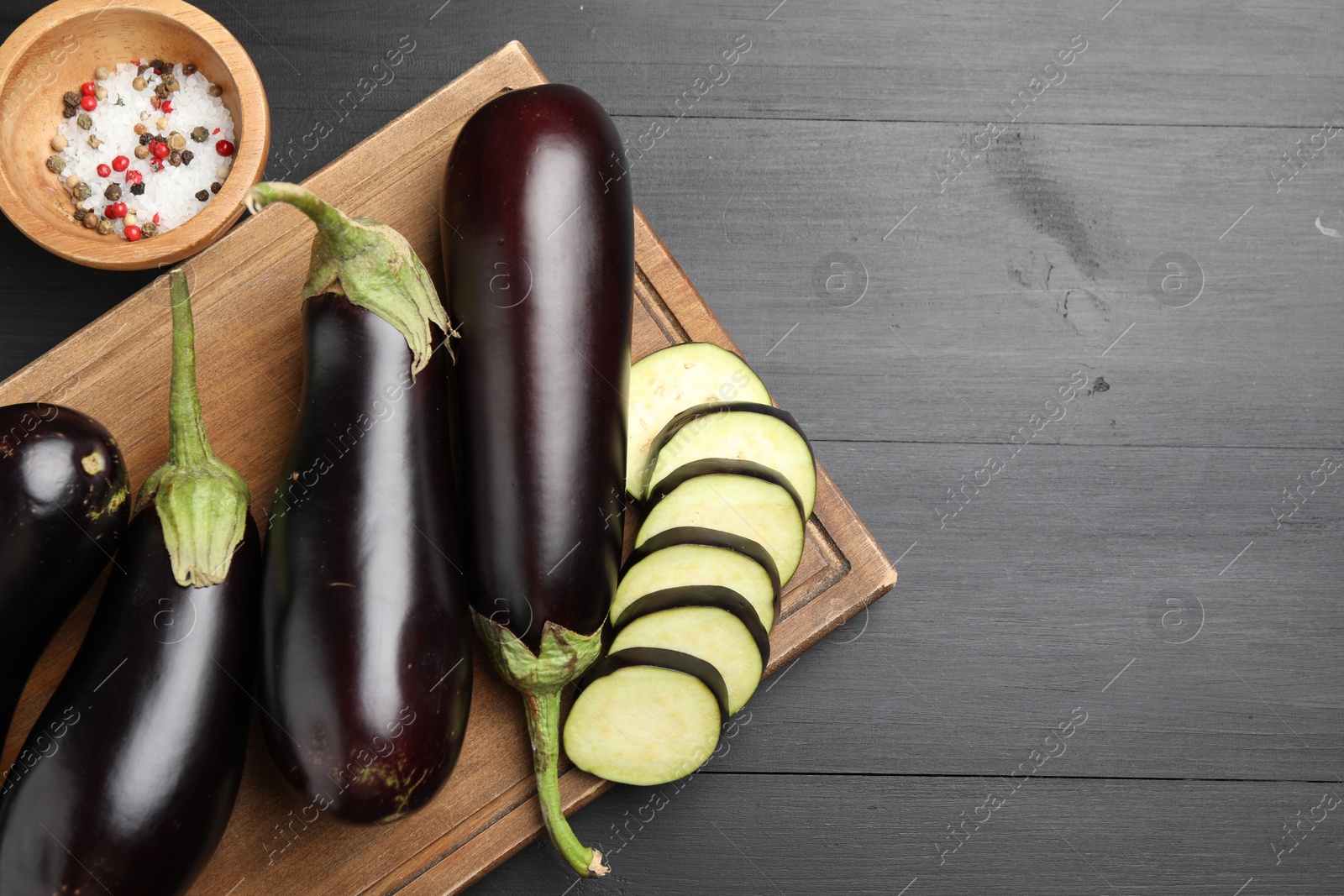 Photo of Fresh eggplants and spices on black wooden table, flat lay. Space for text