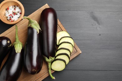 Photo of Fresh eggplants and spices on black wooden table, flat lay. Space for text