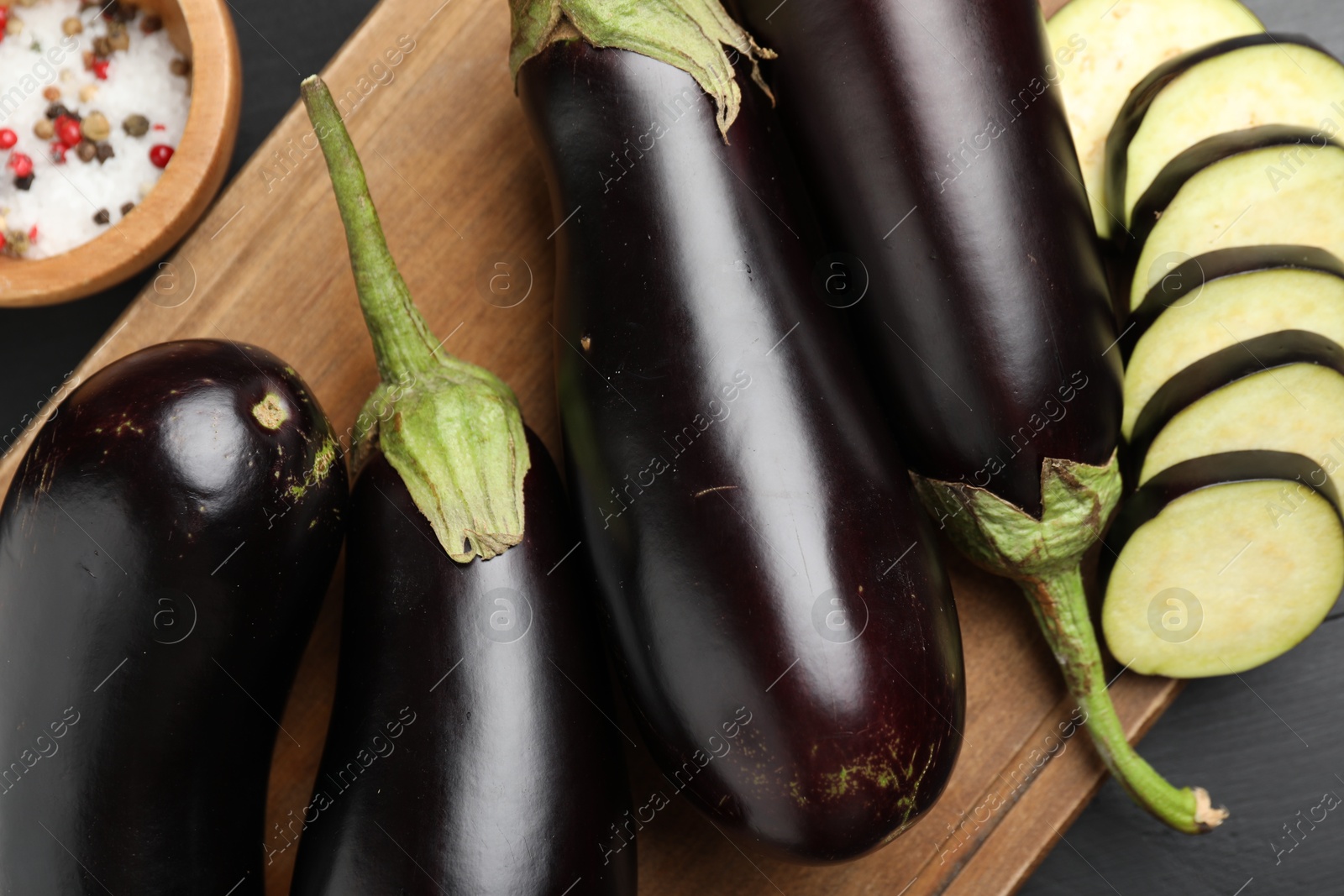Photo of Fresh eggplants and spices on black wooden table, flat lay