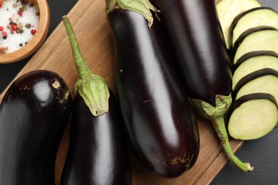 Photo of Fresh eggplants and spices on black wooden table, flat lay