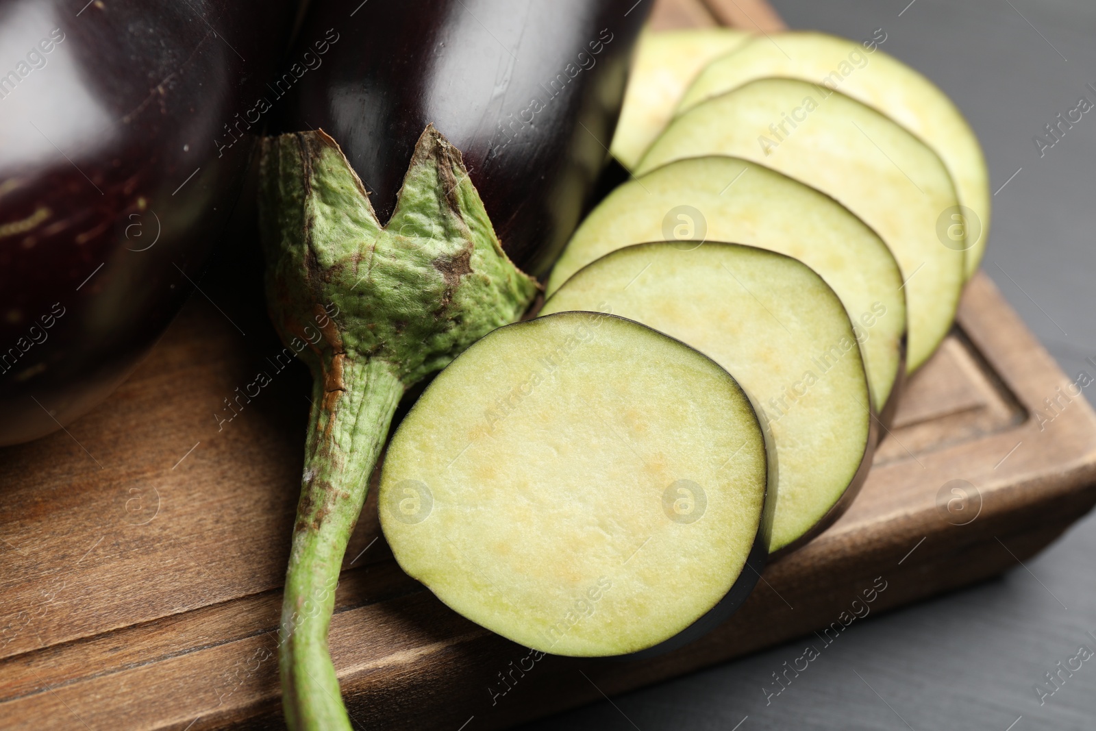 Fresh whole and cut eggplants on black wooden table, closeup Photo of Fresh whole and cut eggplants on black wooden table, closeup