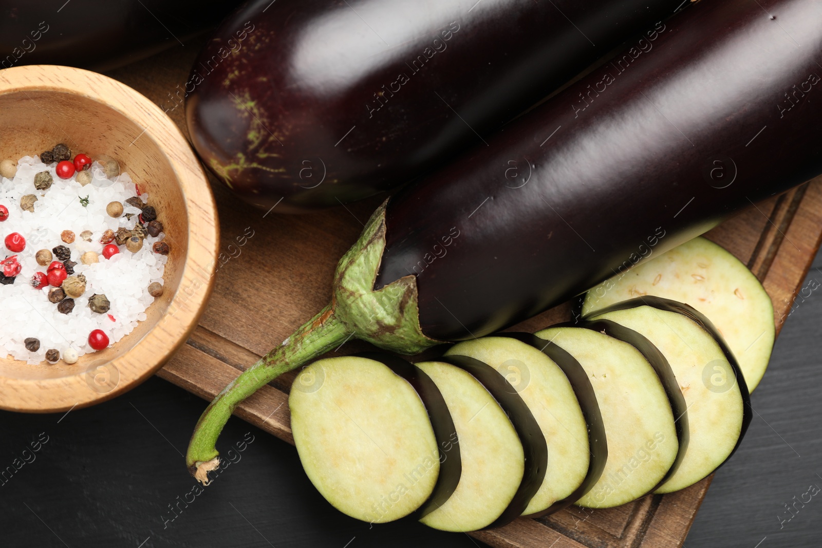 Photo of Fresh eggplants and spices on black wooden table, flat lay