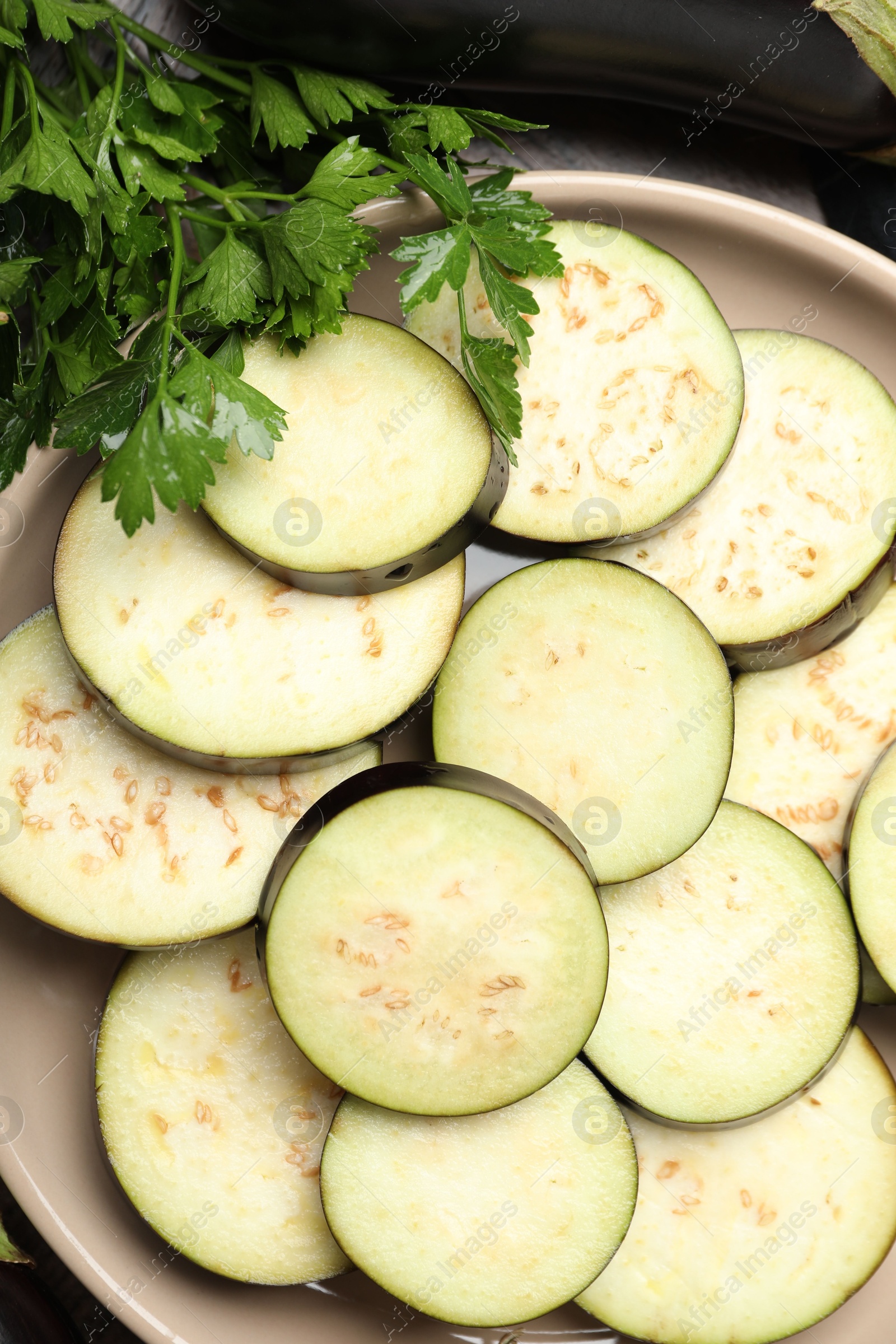 Photo of Slices of fresh eggplants and parsley on wooden table, flat lay