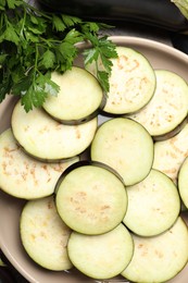 Photo of Slices of fresh eggplants and parsley on wooden table, flat lay