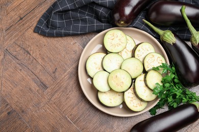 Photo of Slices of fresh eggplants, whole ones and parsley on wooden table, flat lay. Space for text