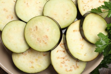 Photo of Slices of fresh eggplants and parsley on table, top view