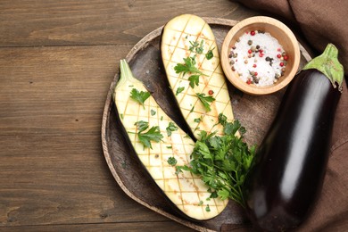 Photo of Halves of fresh eggplant, whole one, spices and parsley on wooden table, top view. Space for text