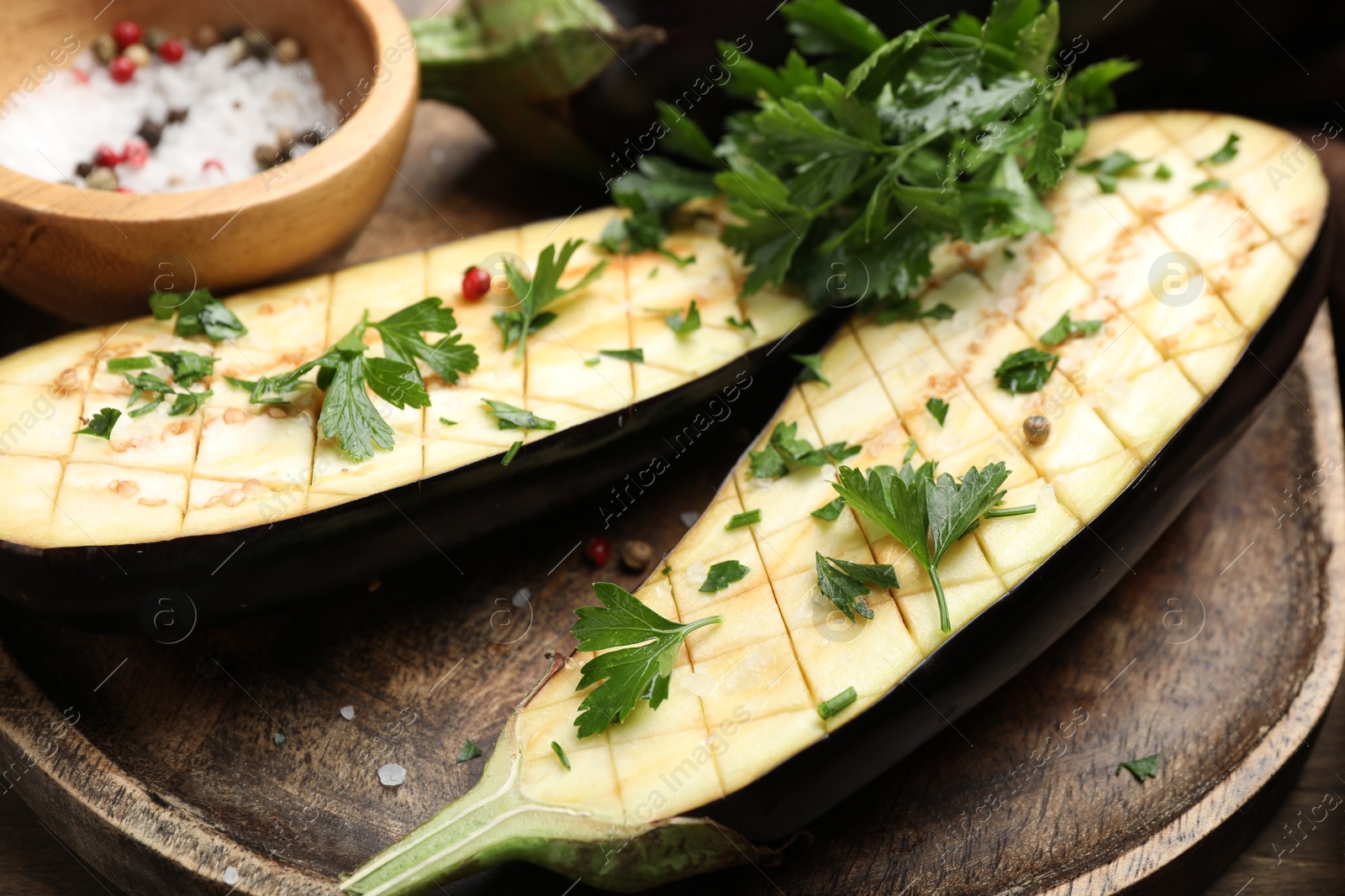 Photo of Halves of fresh eggplant, spices and parsley on wooden table, closeup