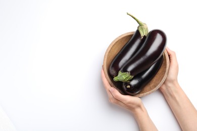 Photo of Woman with bowl of fresh eggplants on white background, top view. Space for text