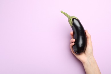 Photo of Woman with fresh eggplant on violet background, top view. Space for text