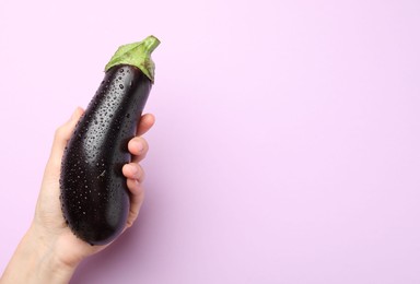Photo of Woman with fresh wet eggplant on violet background, top view. Space for text