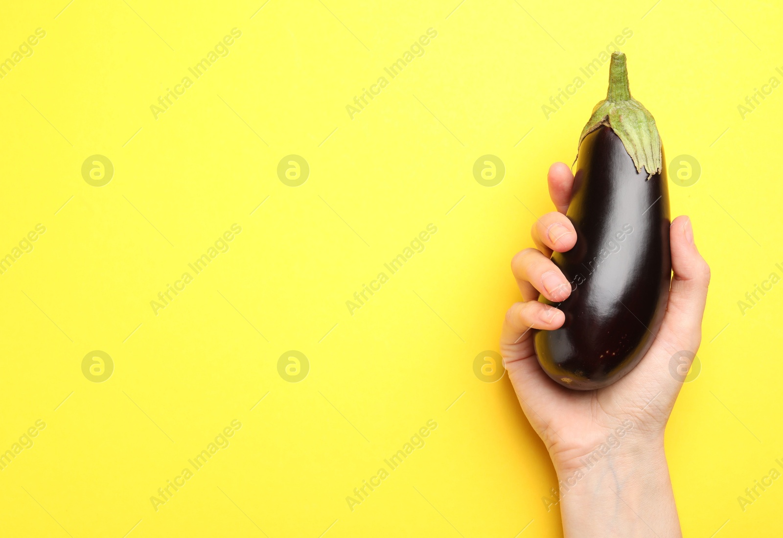 Woman with fresh eggplant on yellow background, top view. Space for text Photo of Woman with fresh eggplant on yellow background, top view. Space for text