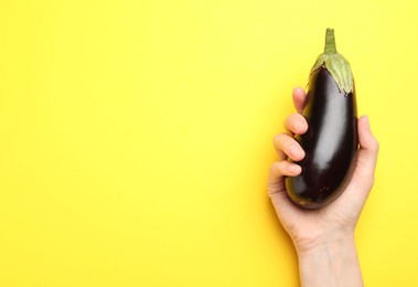 Photo of Woman with fresh eggplant on yellow background, top view. Space for text