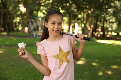 Photo of Portrait of smiling little girl with badminton racket and shuttlecock in park