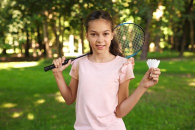 Photo of Portrait of smiling little girl with badminton racket and shuttlecock in park