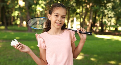 Photo of Portrait of smiling little girl with badminton racket and shuttlecock in park