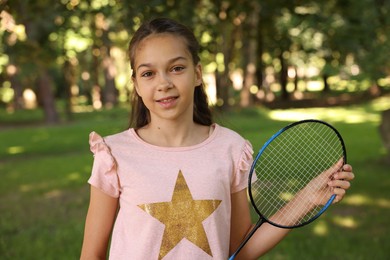 Photo of Portrait of smiling little girl with badminton racket in park