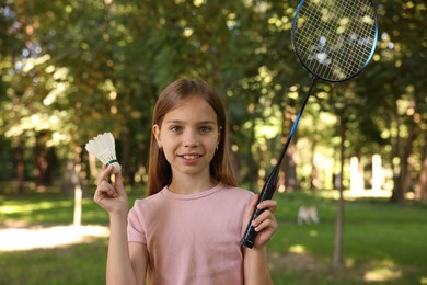 Photo of Portrait of smiling little girl with badminton racket and shuttlecock in park