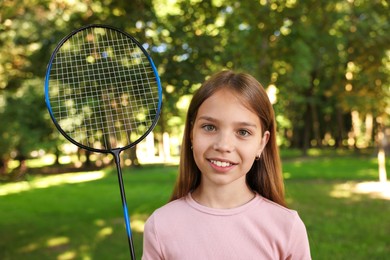 Photo of Portrait of smiling little girl with badminton racket in park